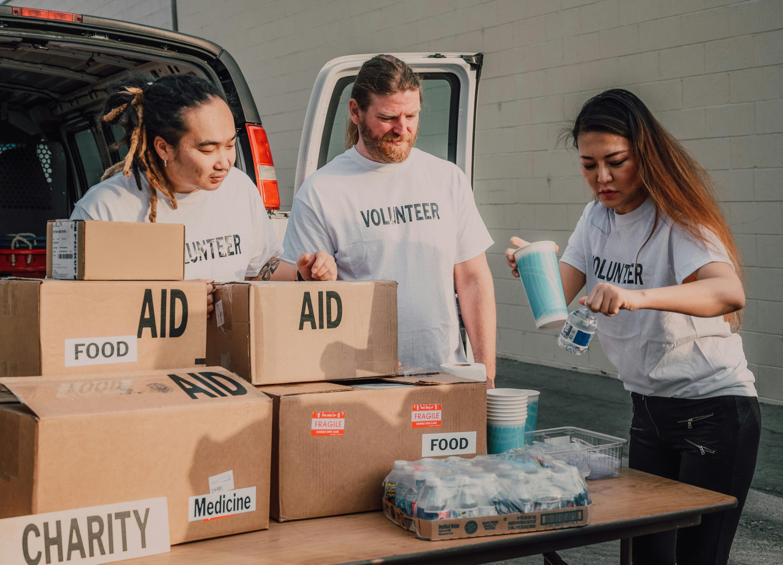 A group of volunteers around boxes labeled Aid. Photo courteousy of Pexels.