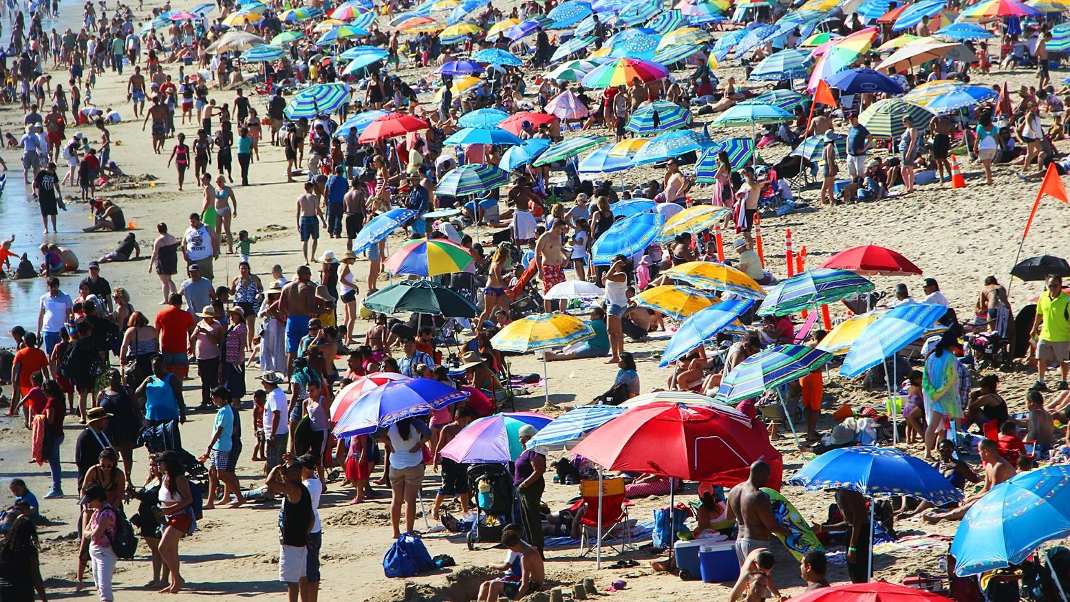 A crowded beach full of people and umbrellas.