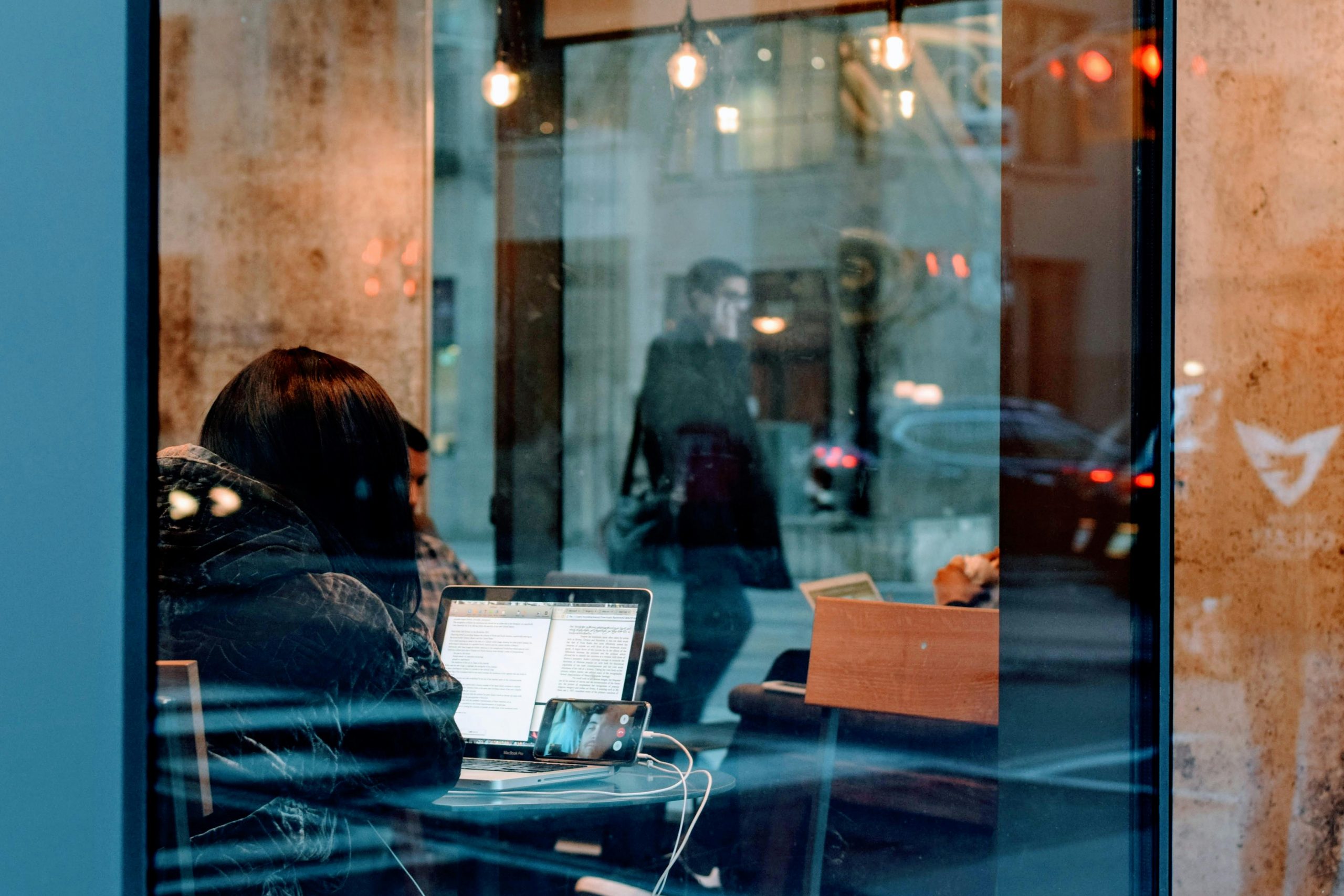 A cafe filled with people can be seen through a glass window.