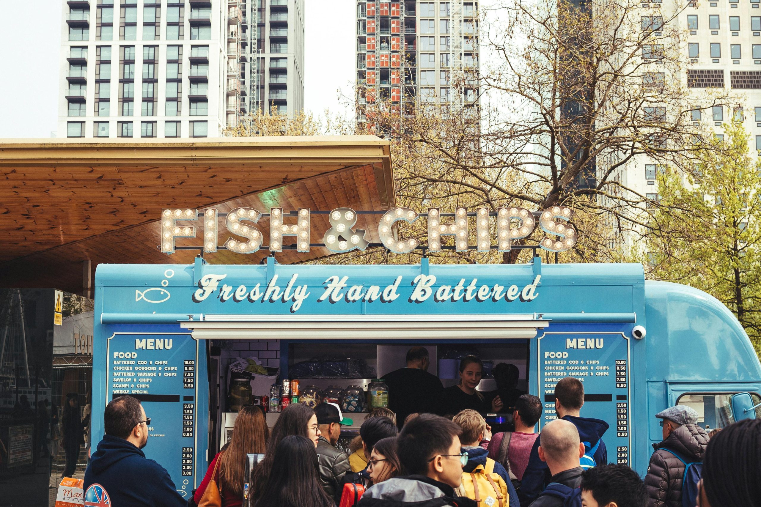 People stand in front of a food truck on a sunny day.