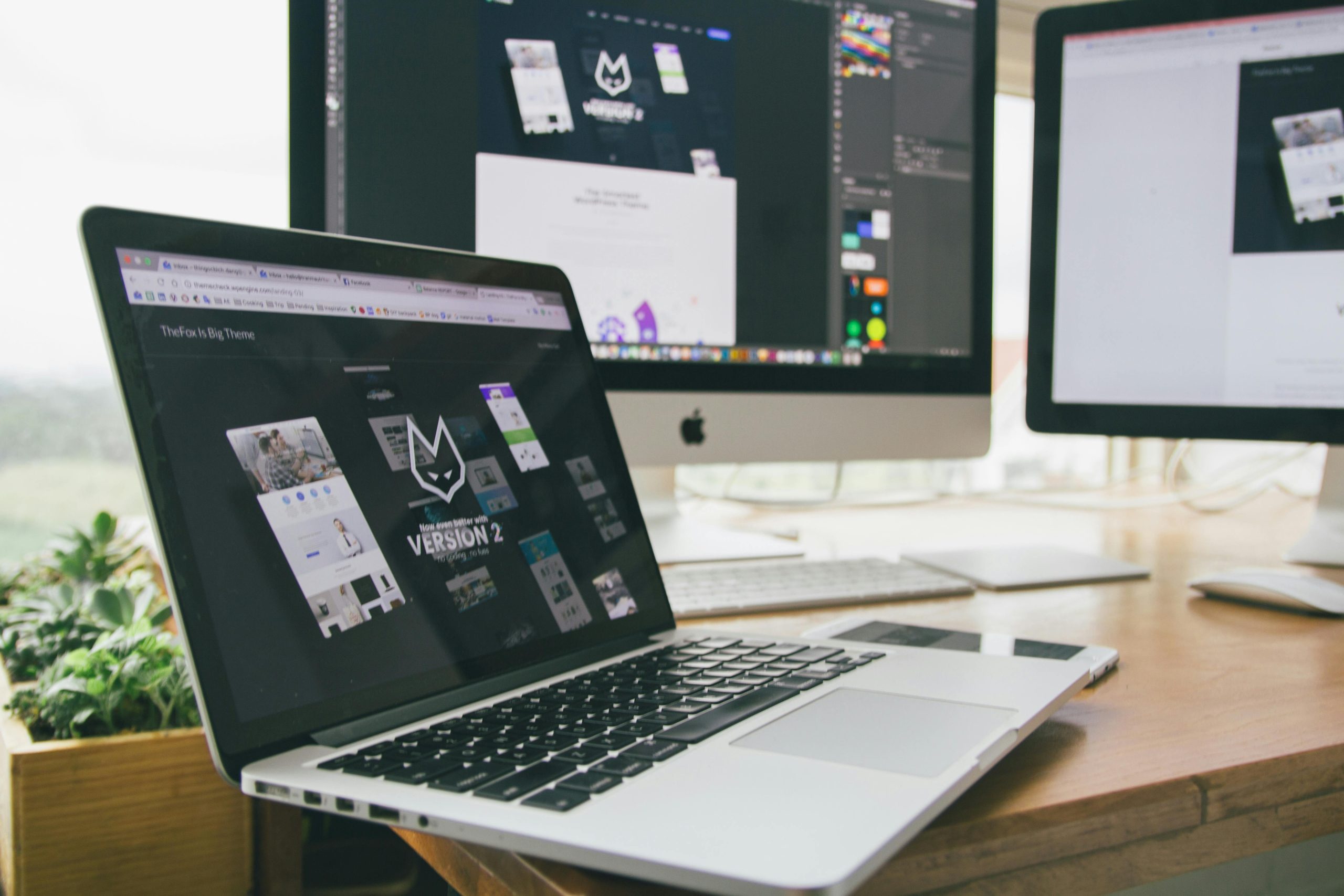 A laptop in front of a desktop computer. Both display branding designs.