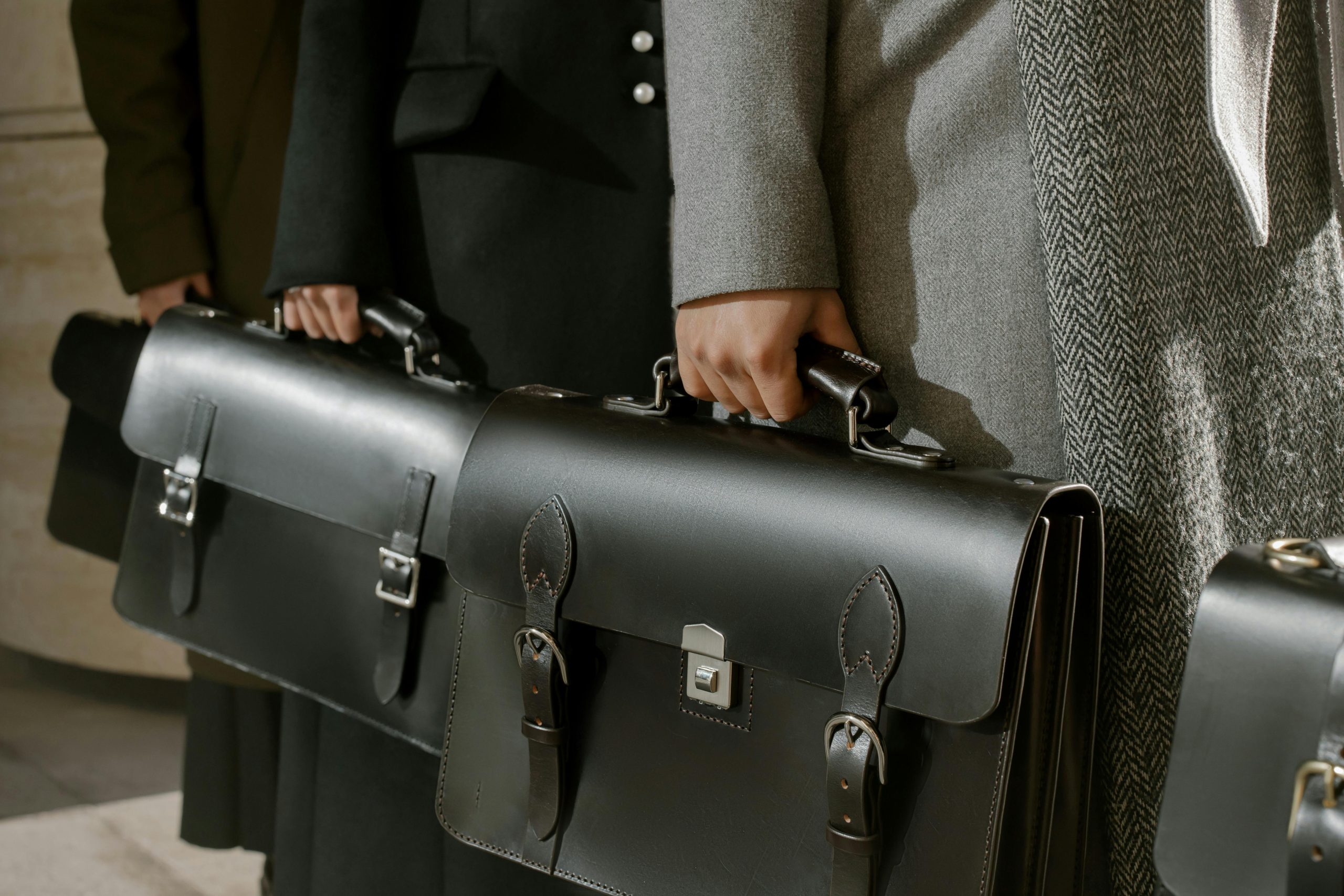 Hands holding onto briefcases.